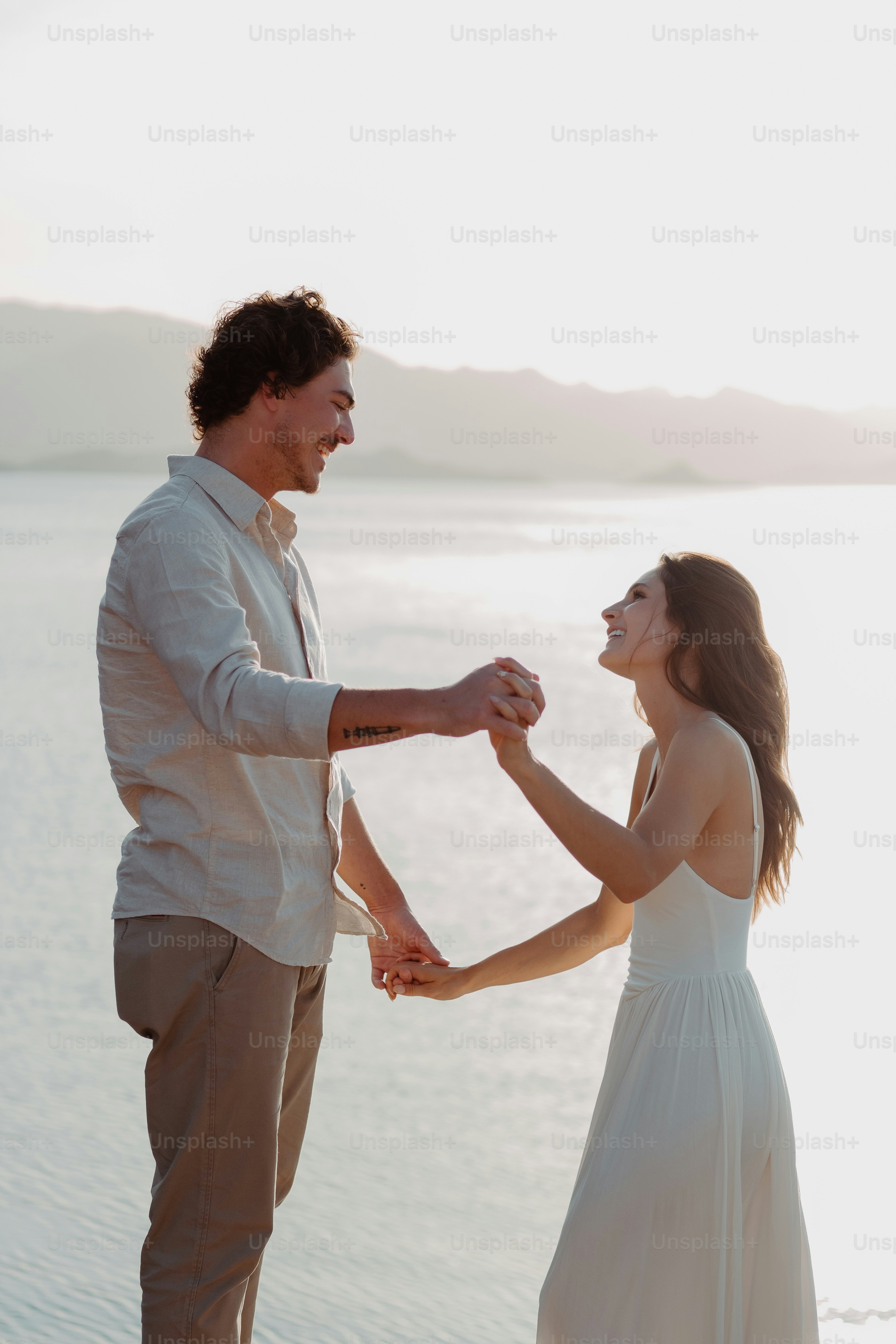 a man and a woman holding hands near the water