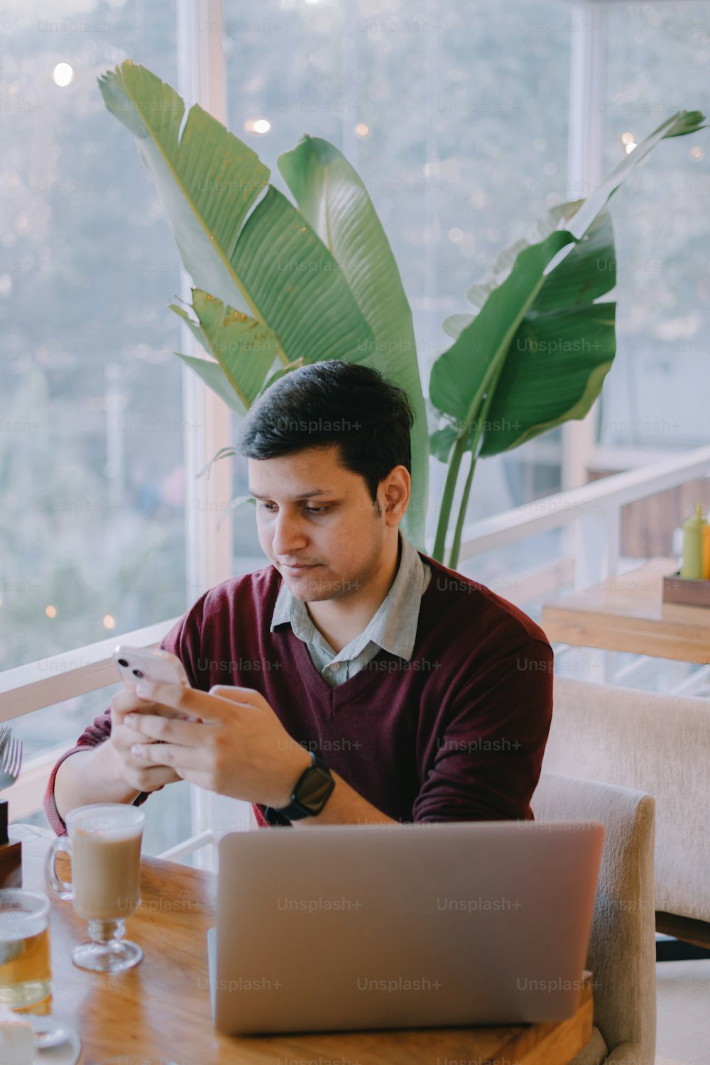 Un homme assis à une table regardant son téléphone portable
