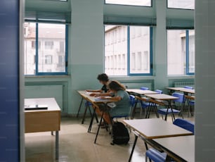 a couple of people sitting at desks in a room