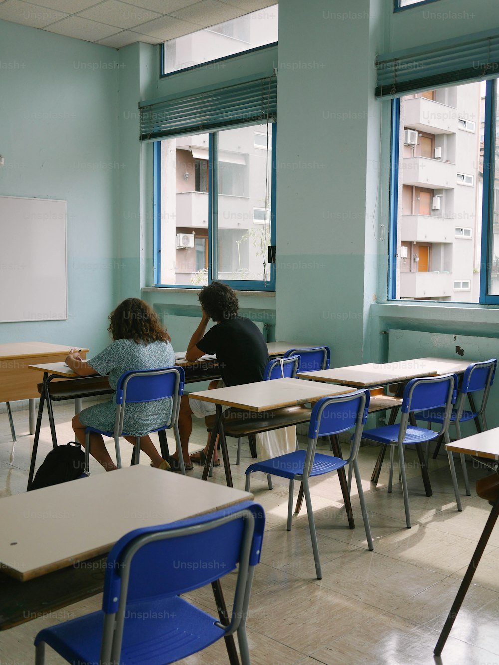 a couple of people sitting at desks in a classroom