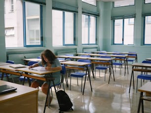 a woman sitting at a desk writing in a classroom