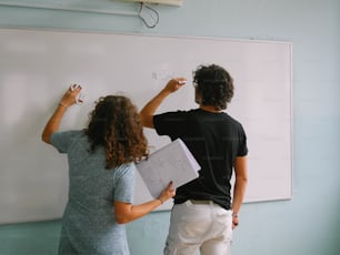 a man and a woman writing on a whiteboard