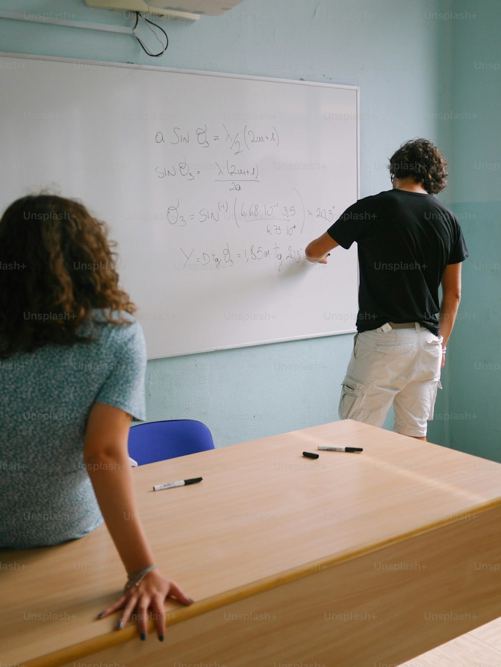 a man and a woman standing in front of a whiteboard