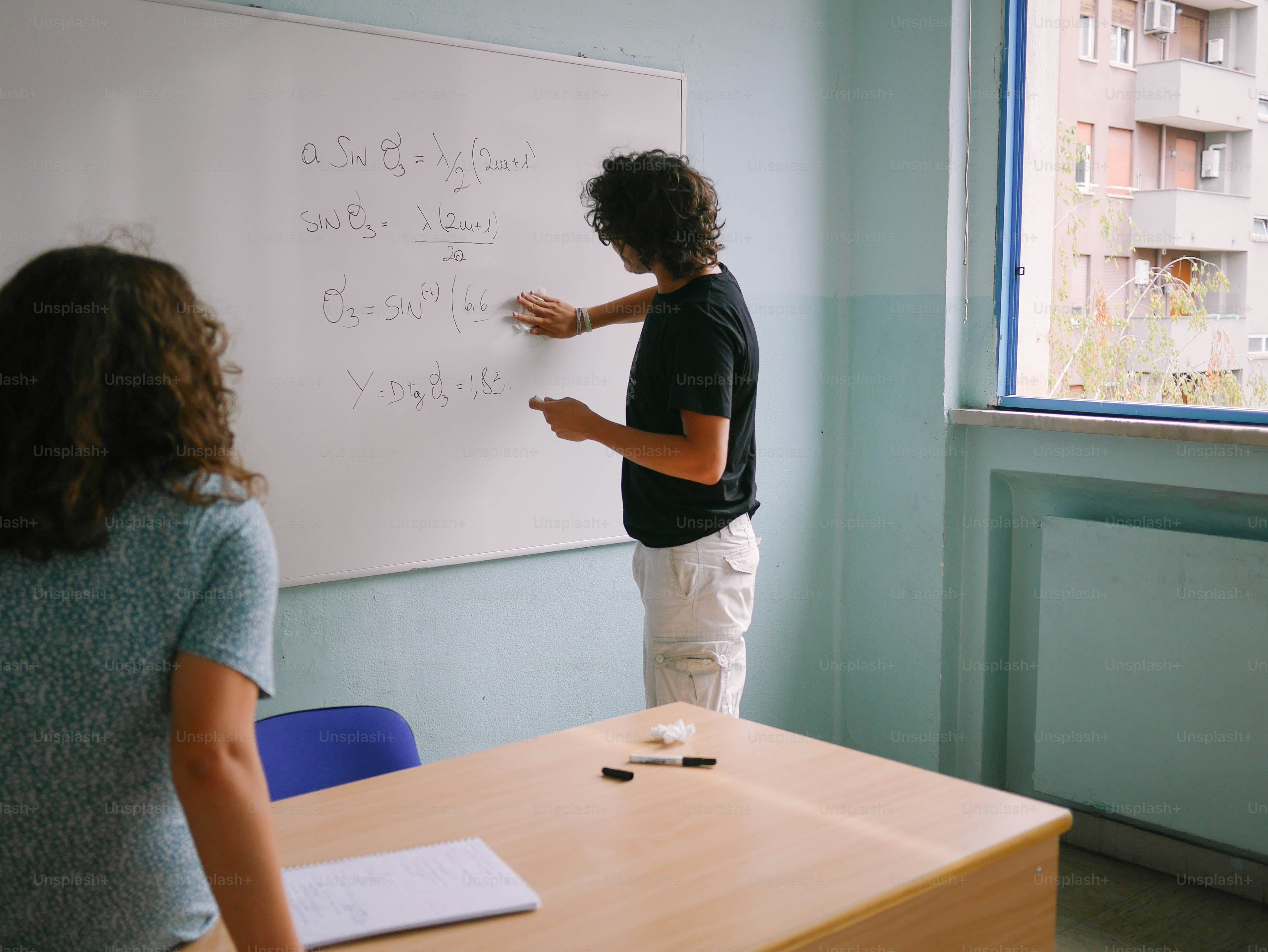 a man and a woman writing on a whiteboard