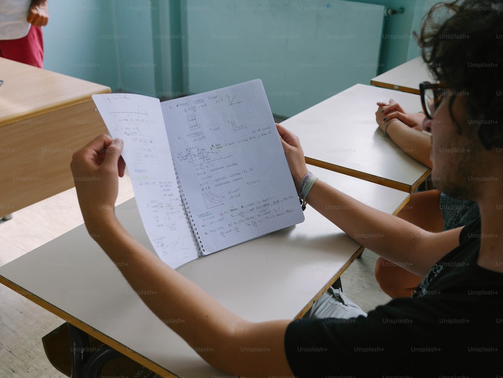 a man sitting at a desk with a notebook in front of him