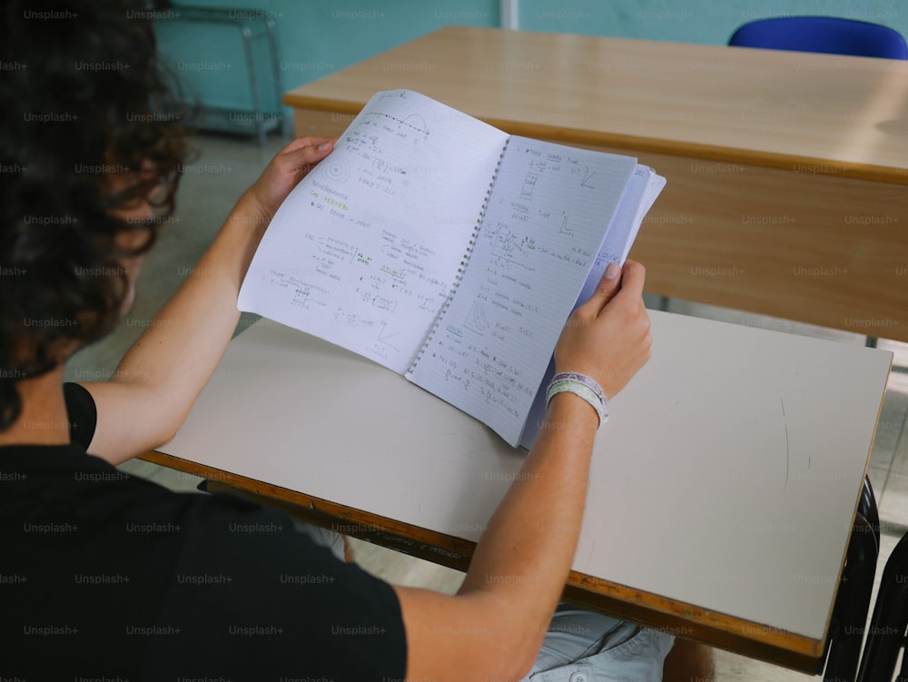 Eine Person, die mit einem offenen Buch an einem Schreibtisch sitzt