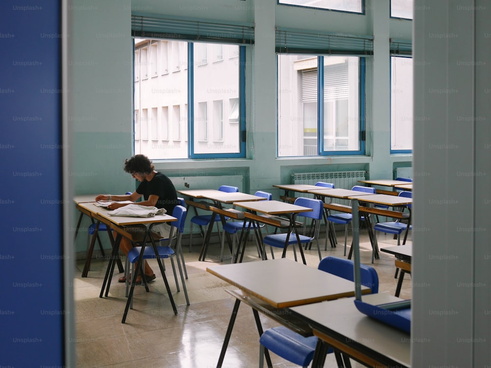 une personne assise à un bureau dans une salle de classe