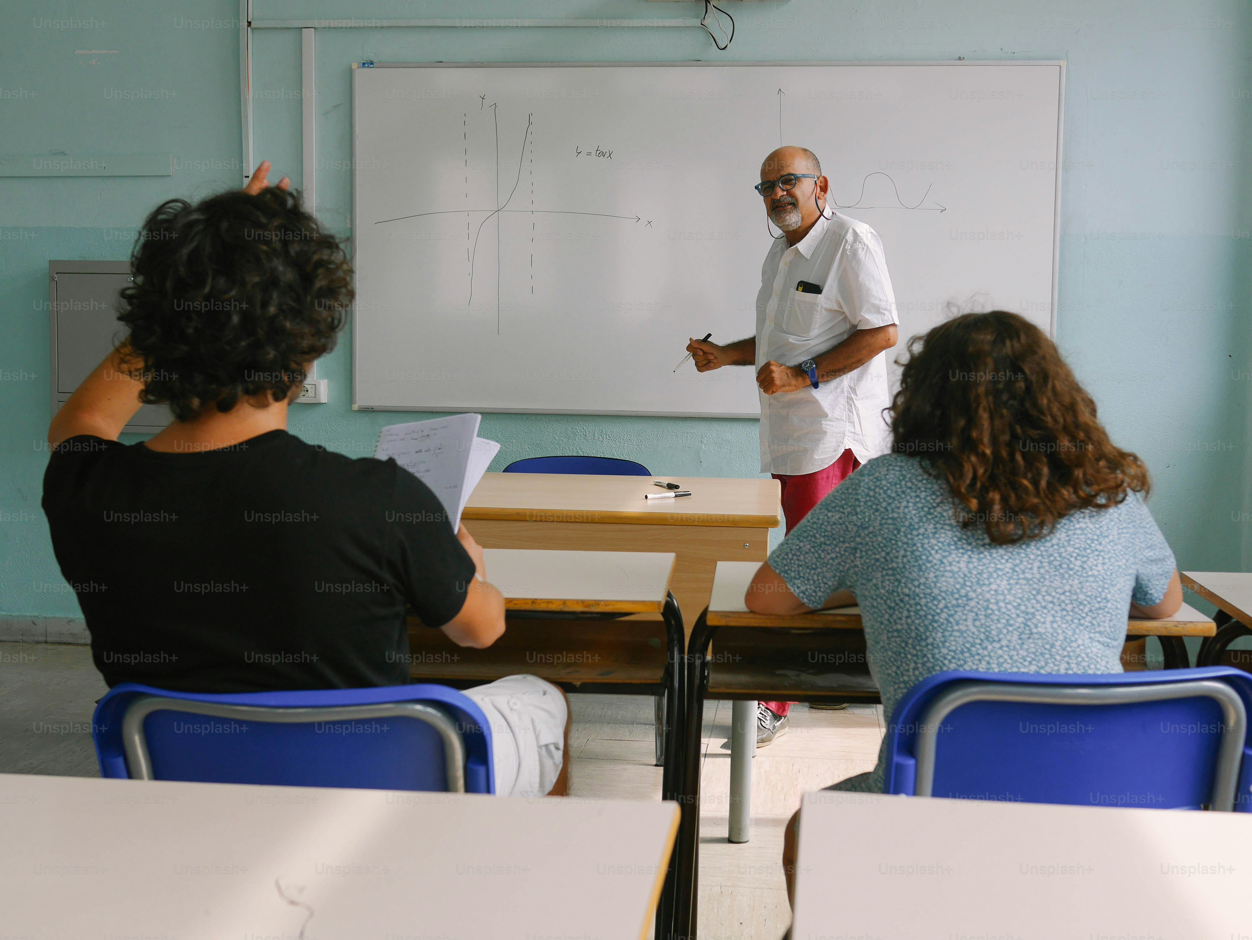 Un uomo in piedi davanti a una lavagna in un'aula