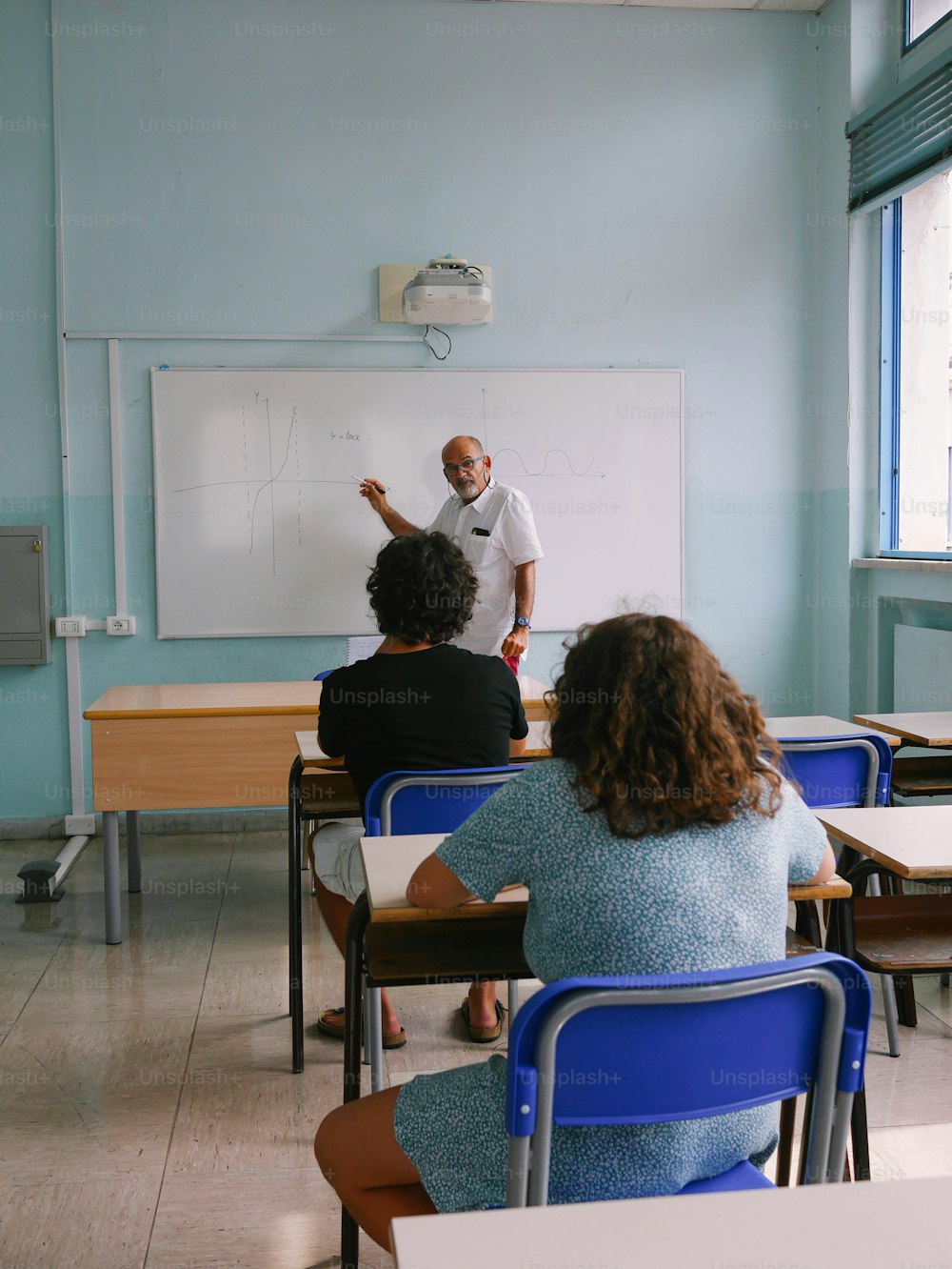 Ein Mann steht vor einem Whiteboard in einem Klassenzimmer
