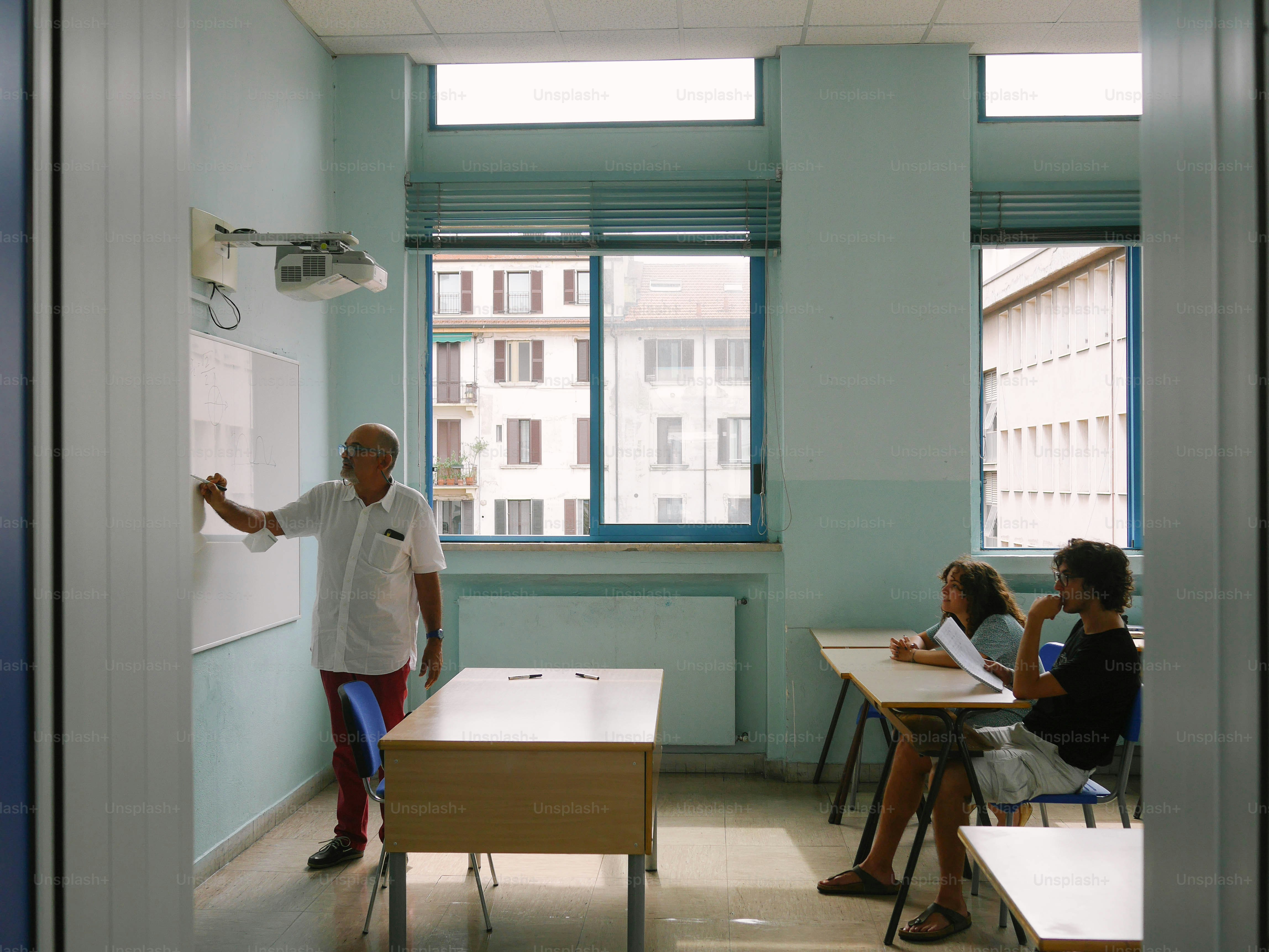 a man standing in front of a whiteboard in a classroom