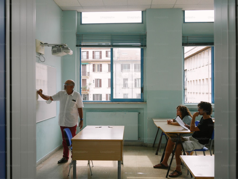Un uomo in piedi davanti a una lavagna in un'aula