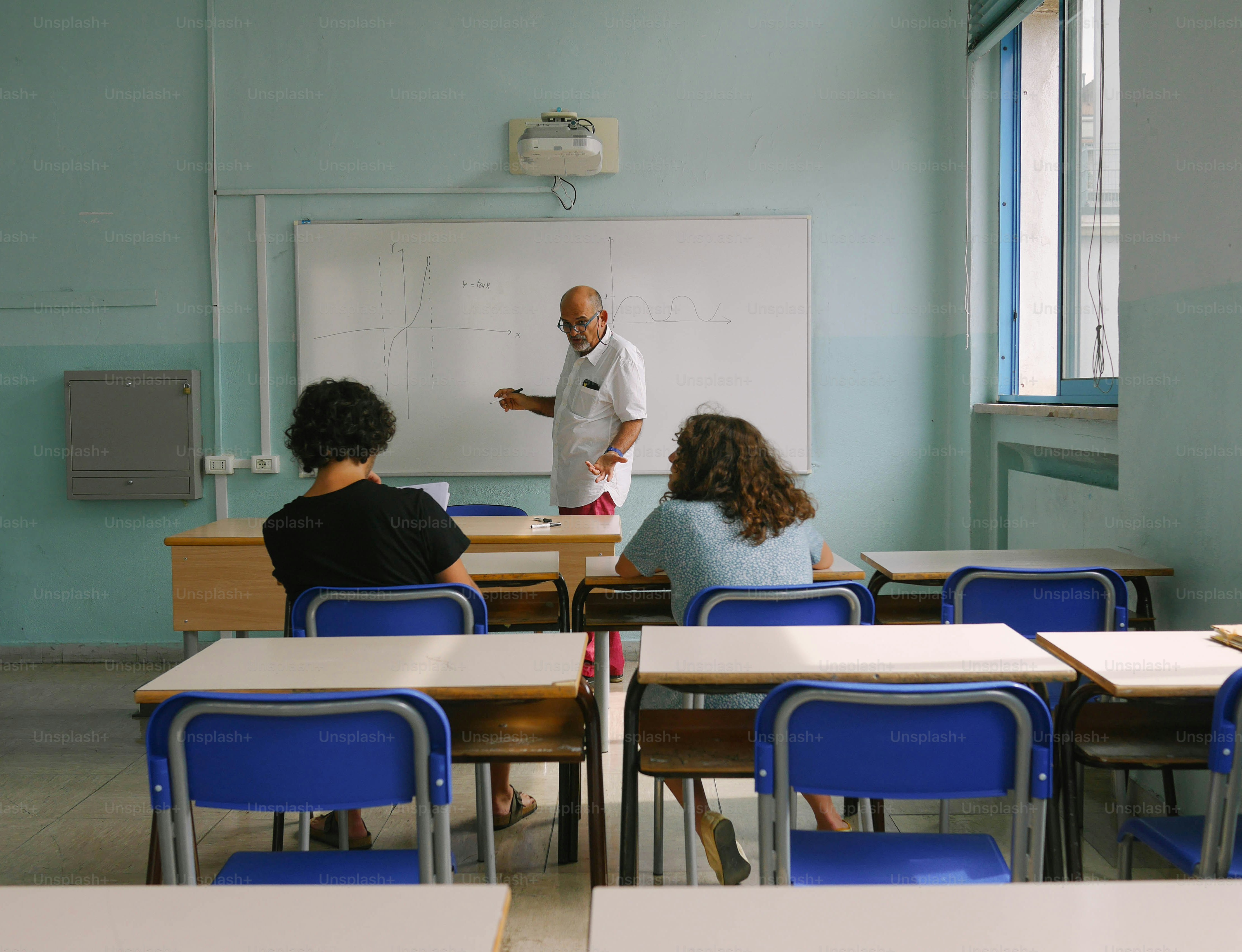 a man standing in front of a whiteboard in a classroom