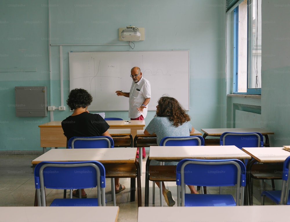 Un homme debout devant un tableau blanc dans une salle de classe