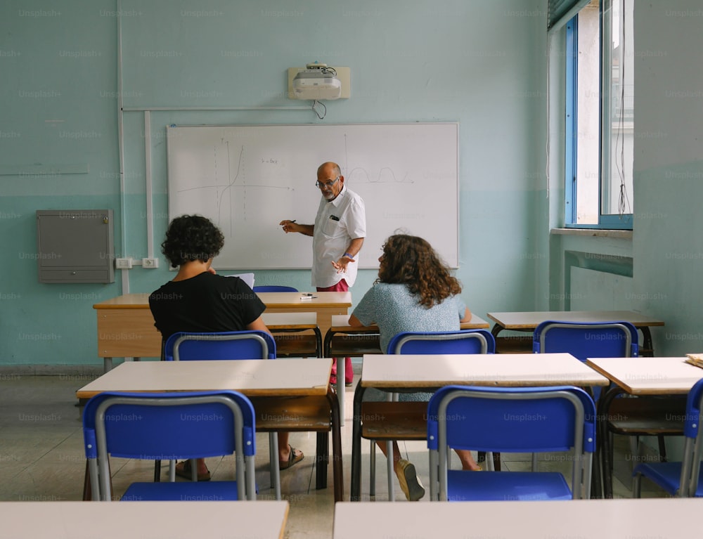 um homem em pé na frente de um quadro branco em uma sala de aula
