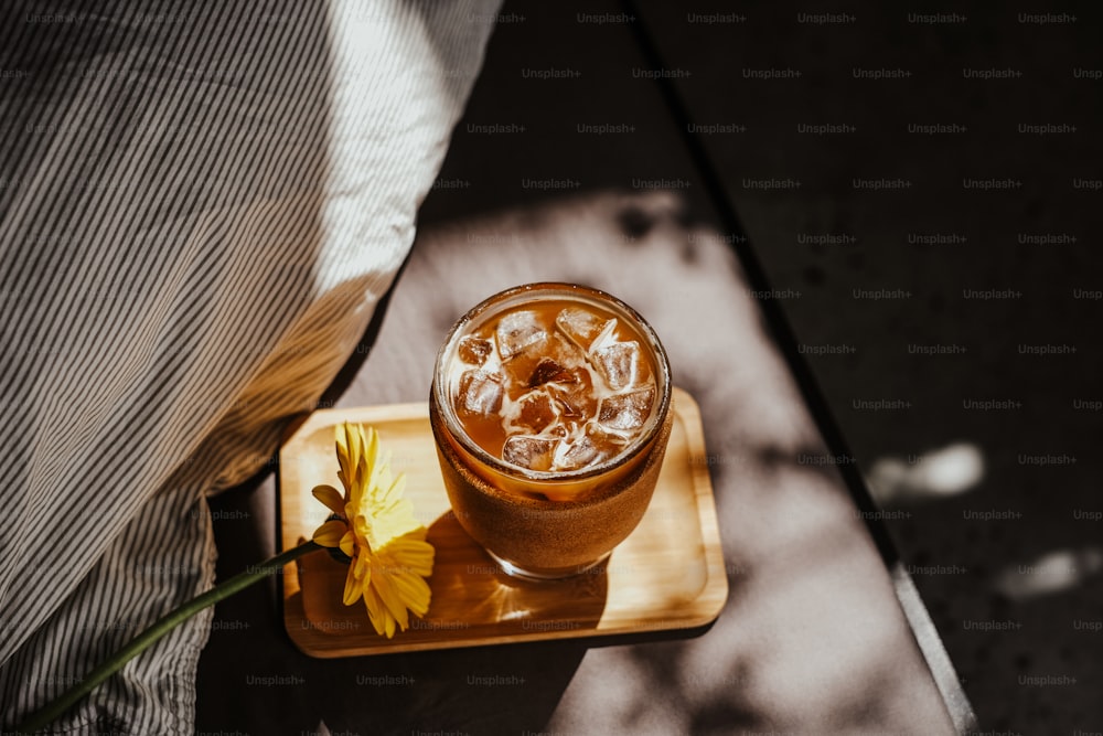 a drink with ice and a flower on a tray