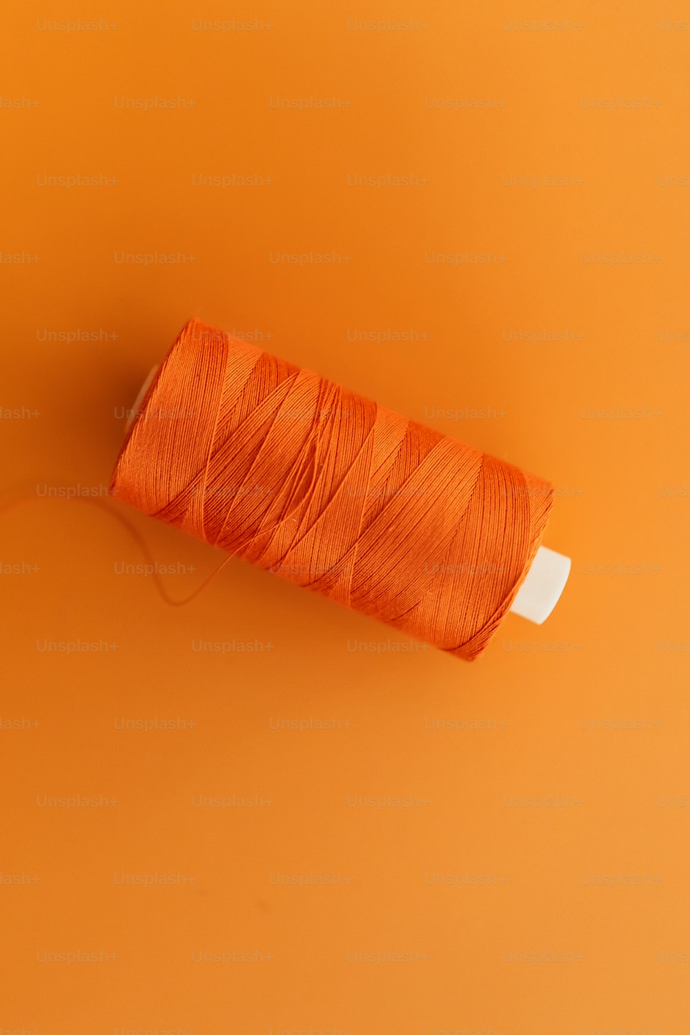 eine Spule aus orangefarbenem Faden auf orangefarbenem Hintergrund