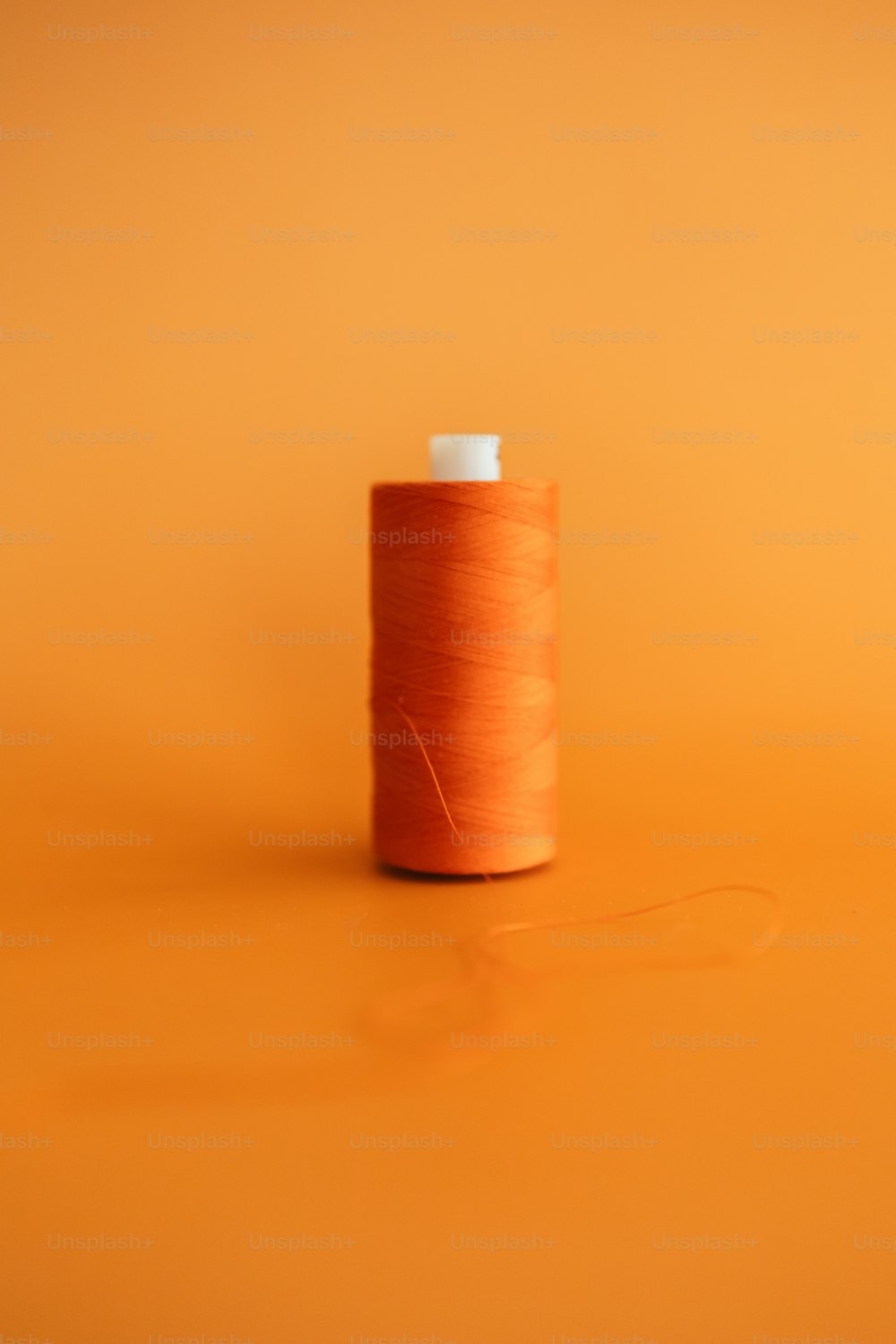a spool of thread on an orange background