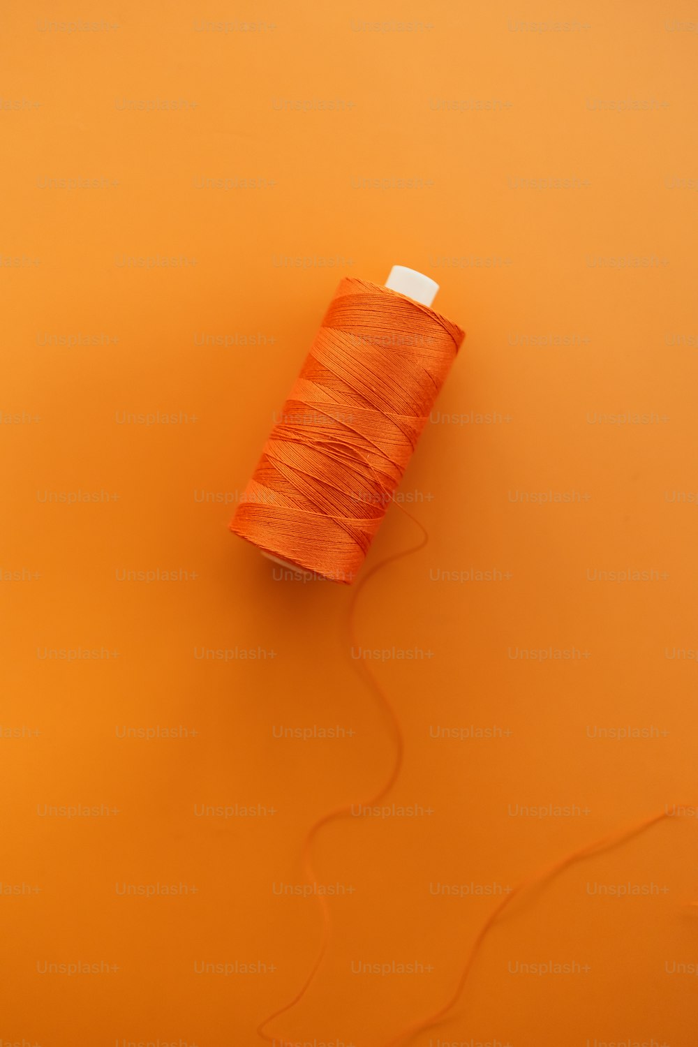 a spool of thread on an orange background