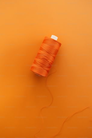 a spool of thread on an orange background
