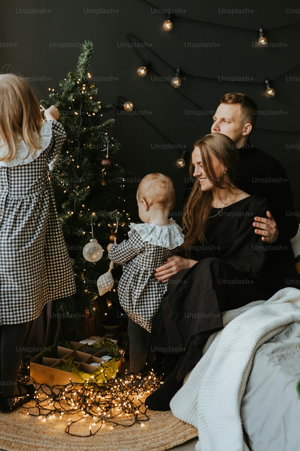 uma família em pé na frente de uma árvore de Natal