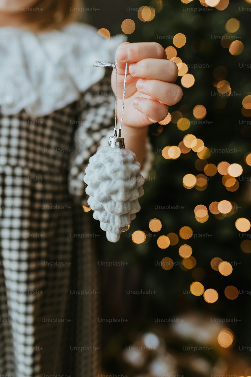 a little girl holding a christmas ornament in front of a christmas tree