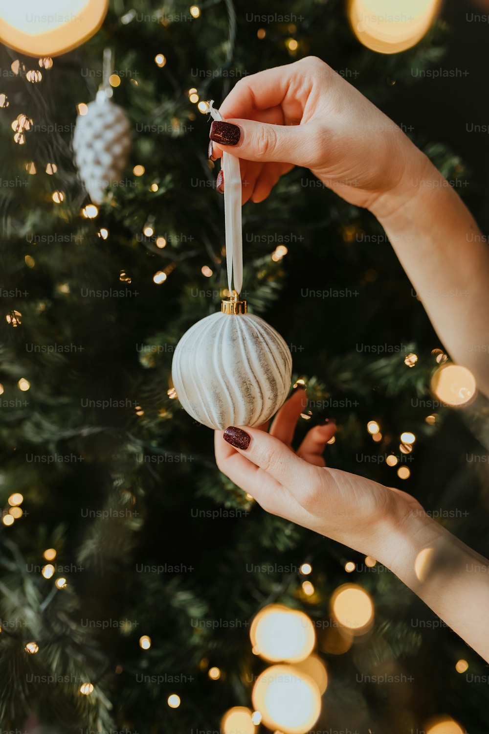 a woman holding a white ornament in front of a christmas tree