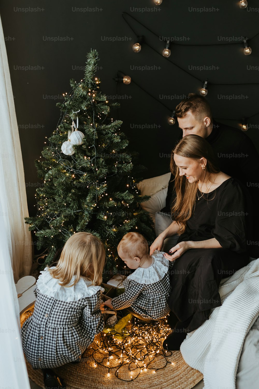 a family sitting on a bed in front of a christmas tree