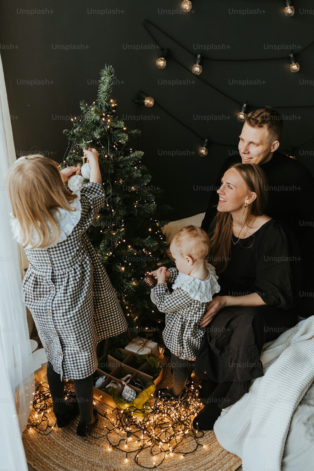 a family sitting on a bed next to a christmas tree