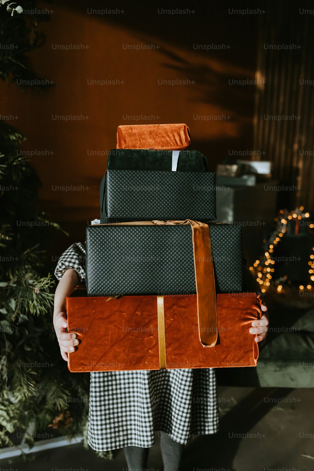 a woman holding a stack of luggage in front of a christmas tree