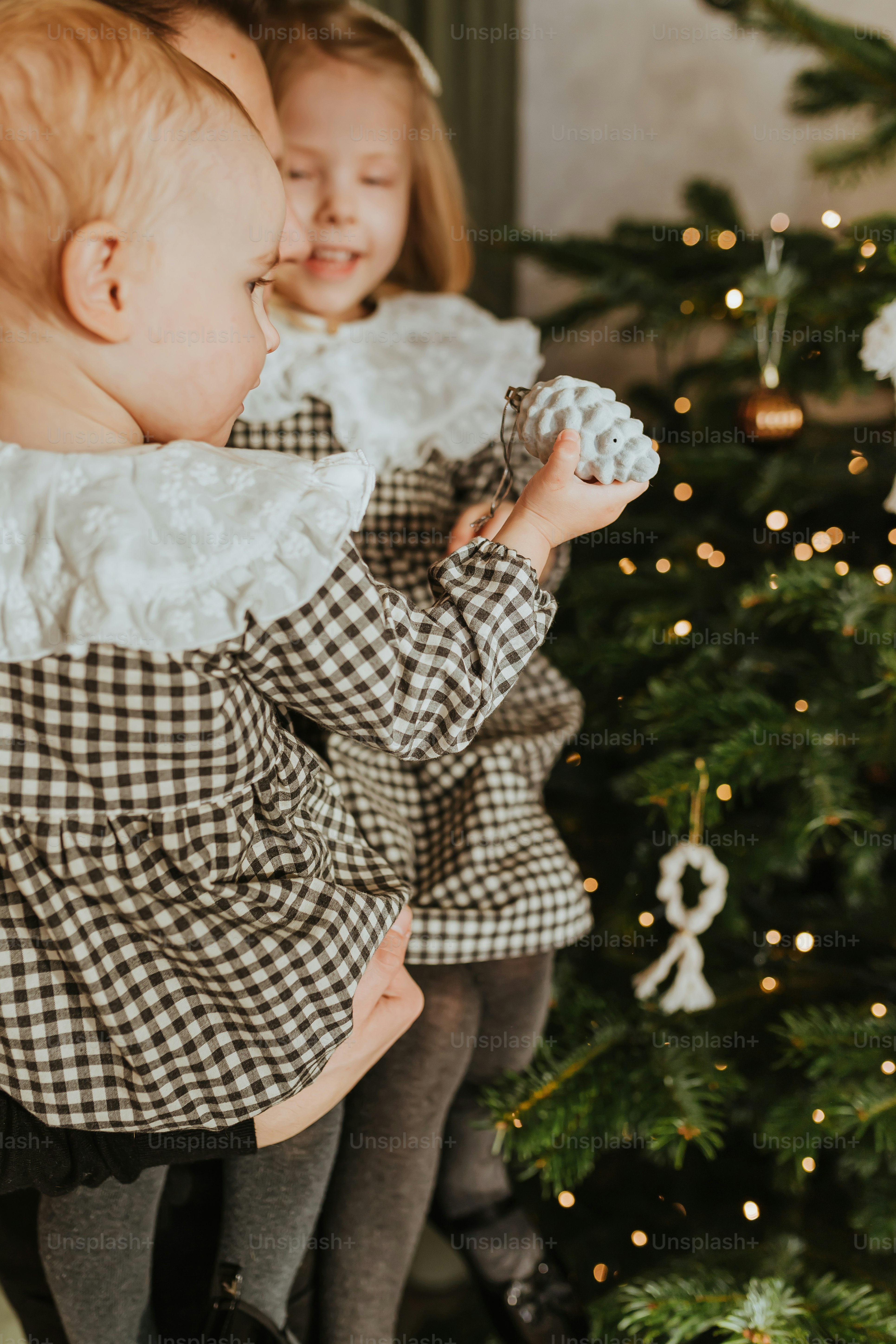 a woman holding a baby in front of a christmas tree