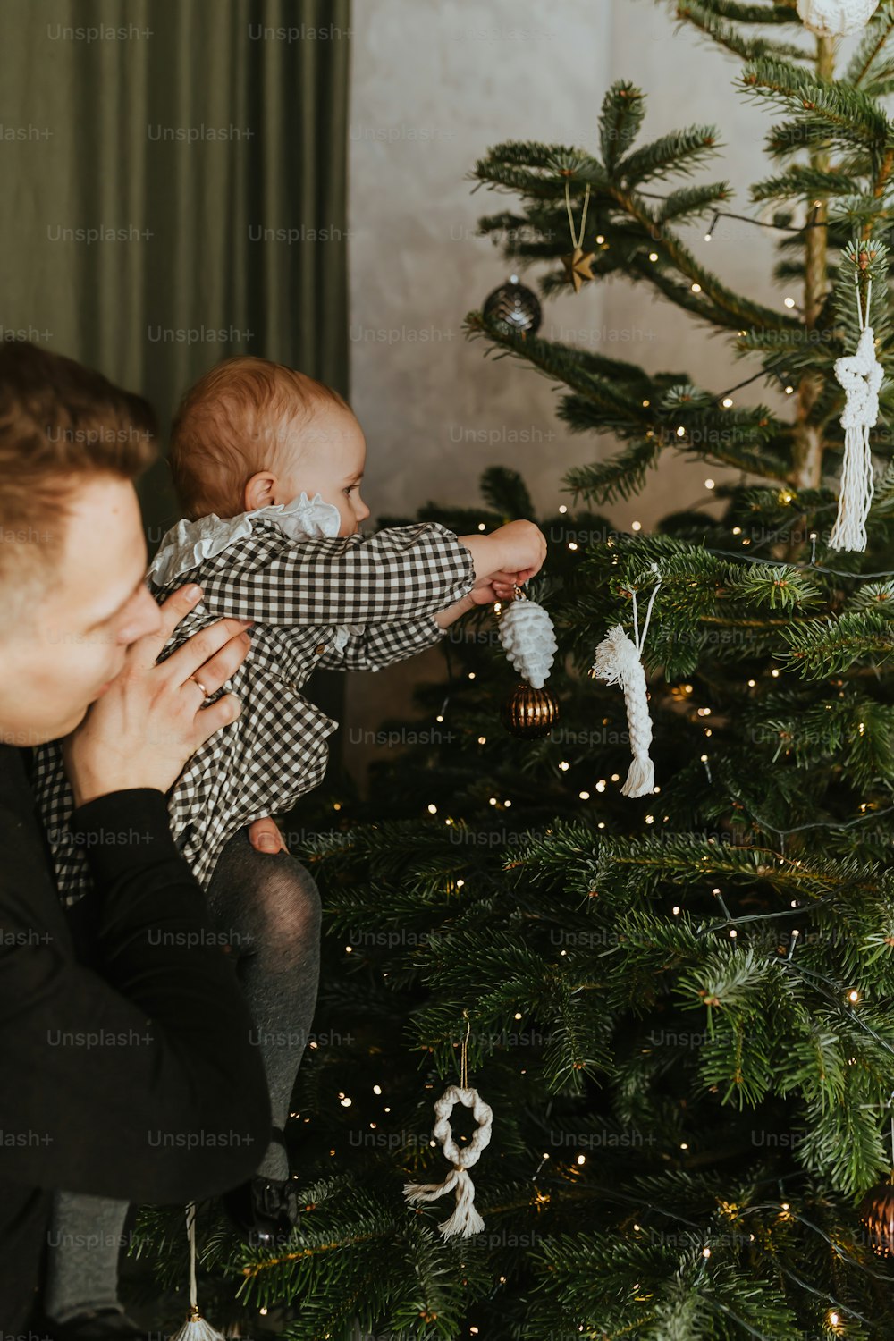 Una donna che tiene un bambino davanti a un albero di Natale
