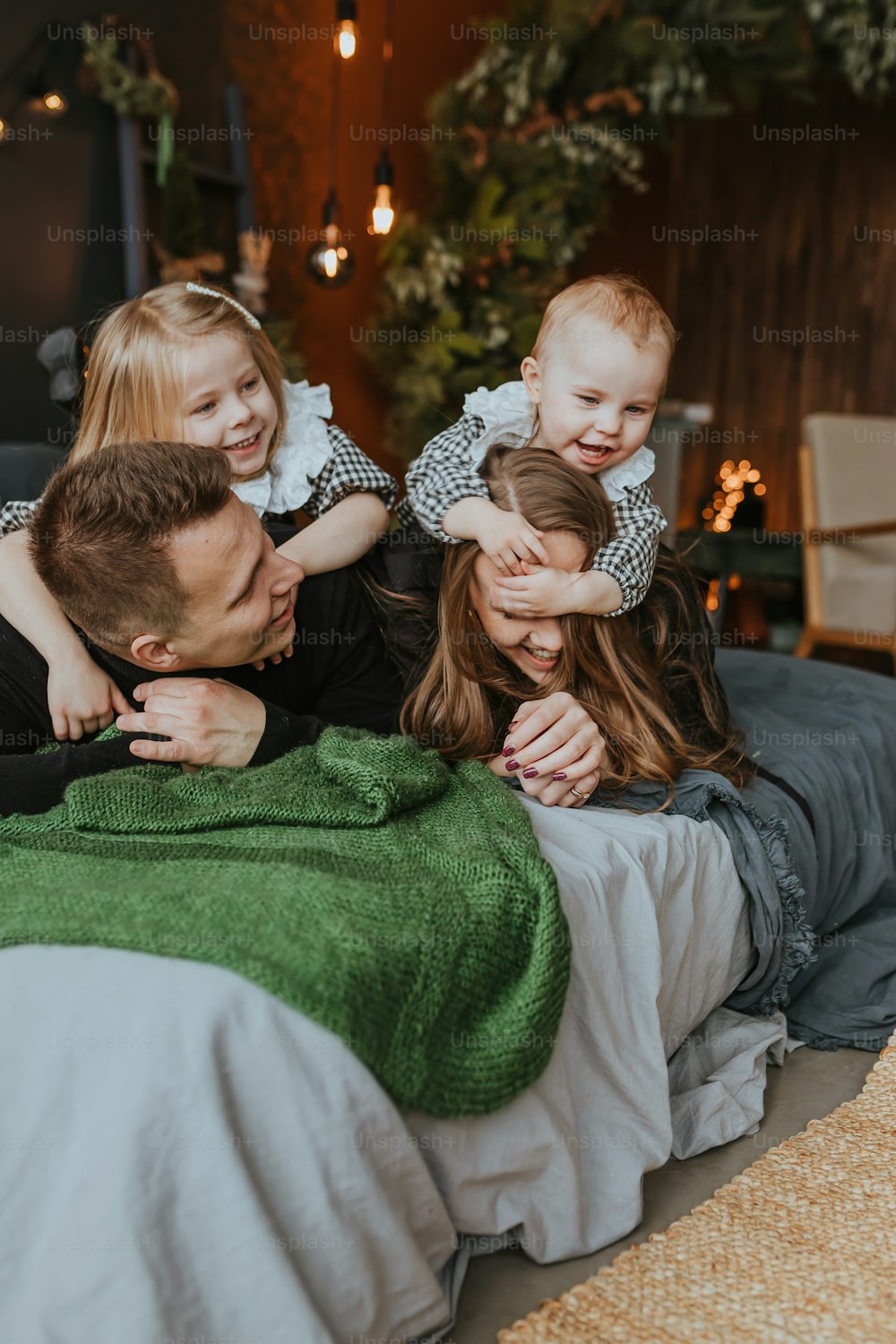 a family laying on a bed with a green blanket