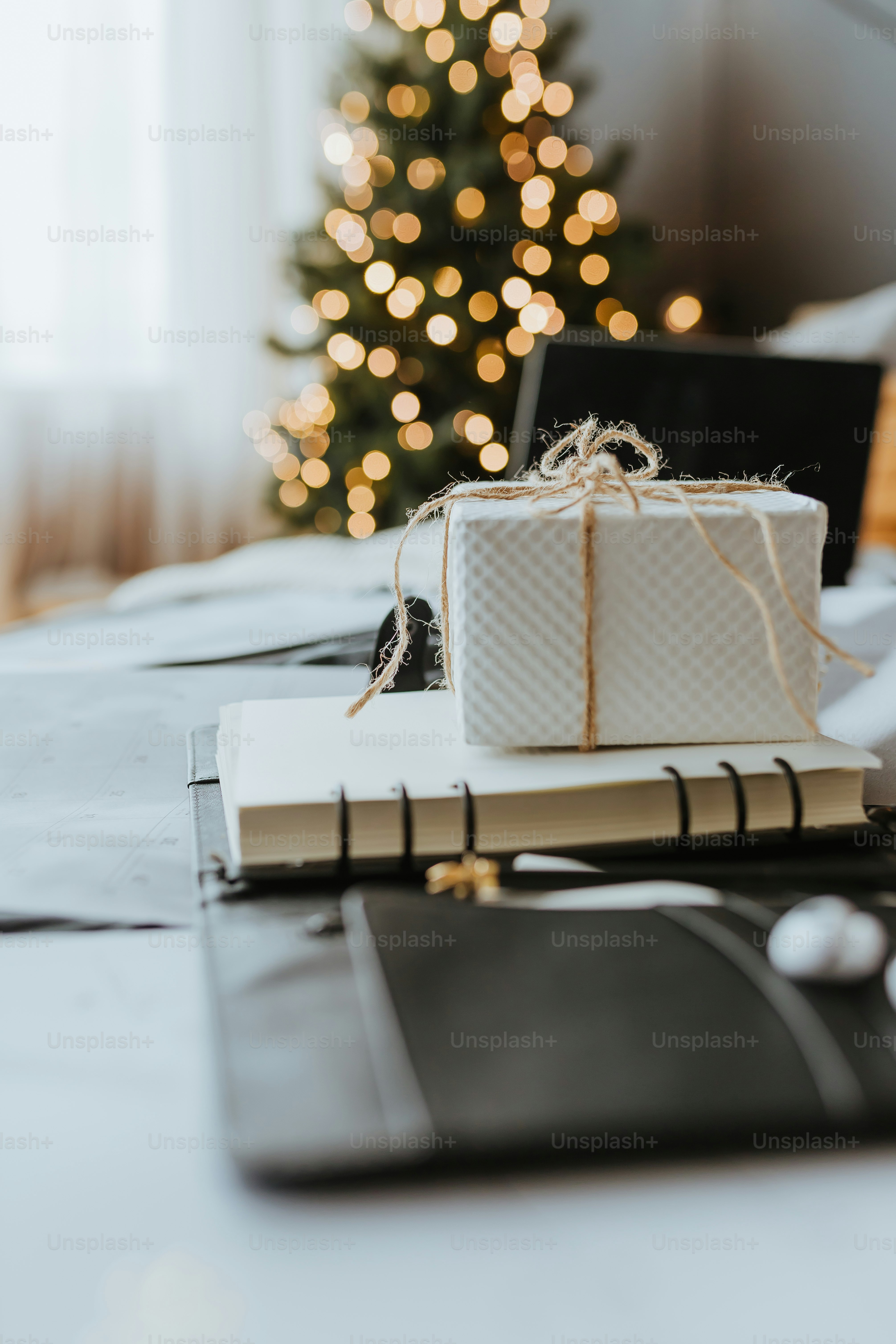 um presente sentado em cima de um livro ao lado de uma árvore de Natal