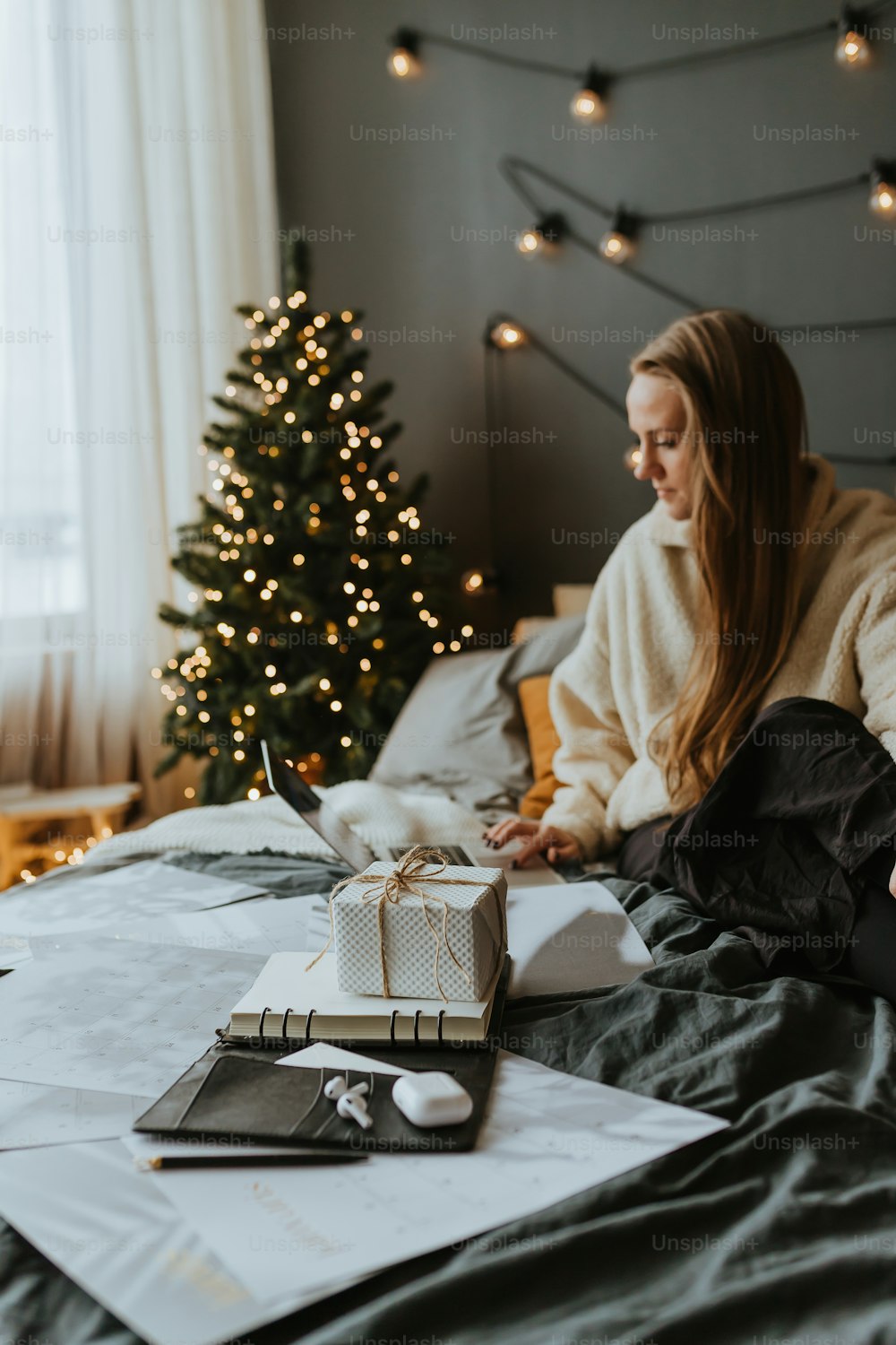 a woman sitting on a bed next to a christmas tree