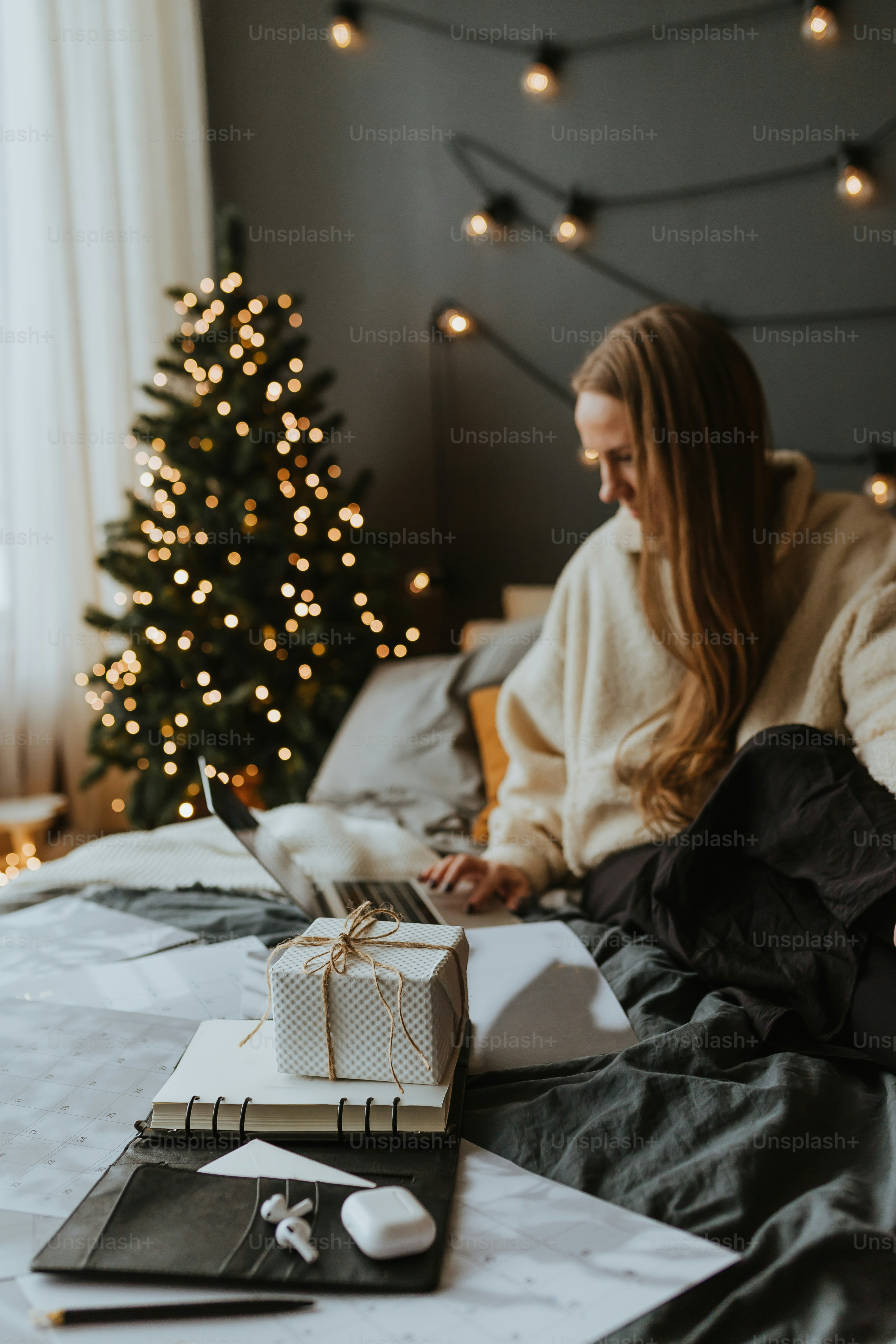 uma mulher sentada em uma cama usando um laptop