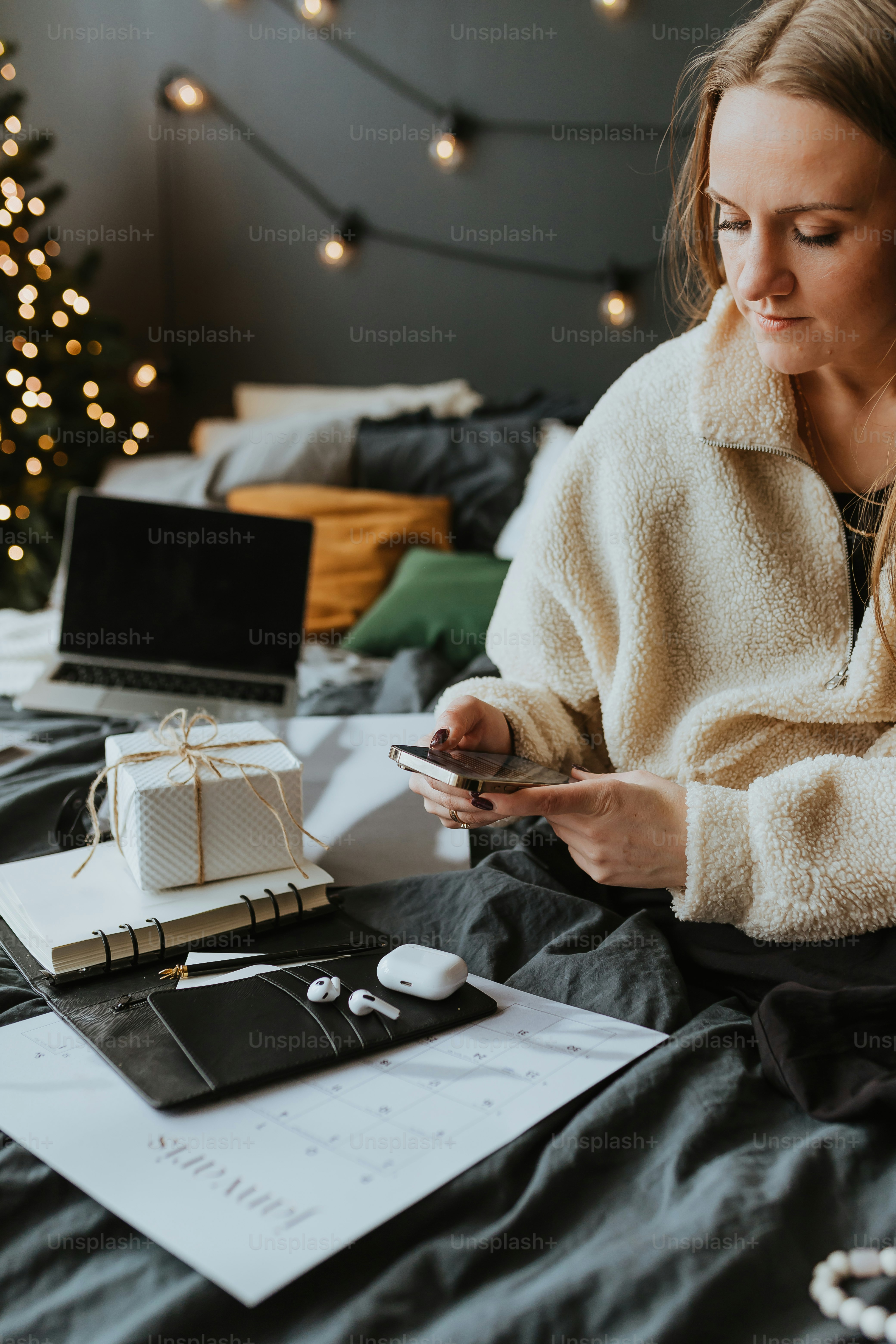 uma mulher sentada em uma cama olhando para seu telefone celular