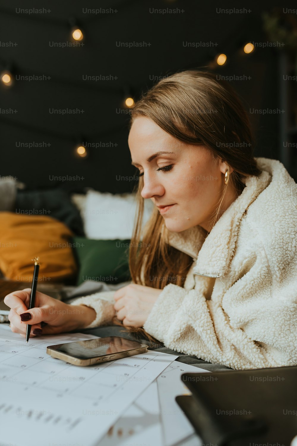 Eine Frau sitzt am Schreibtisch und schreibt auf ein Blatt Papier