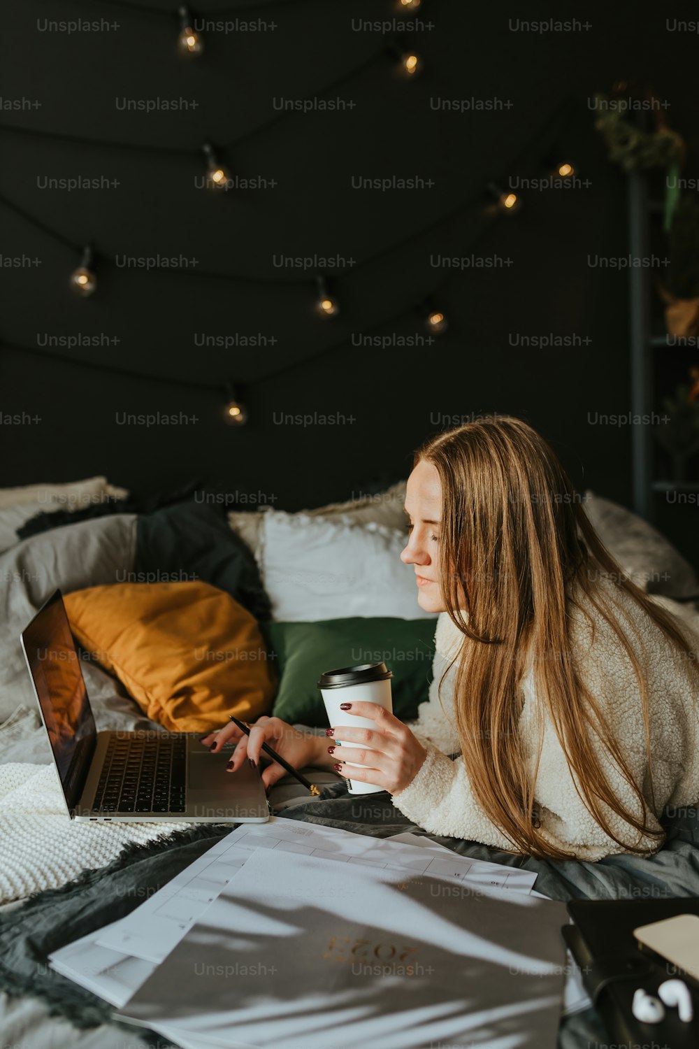 Eine Frau sitzt auf einem Bett und hält eine Tasse Kaffee in der Hand