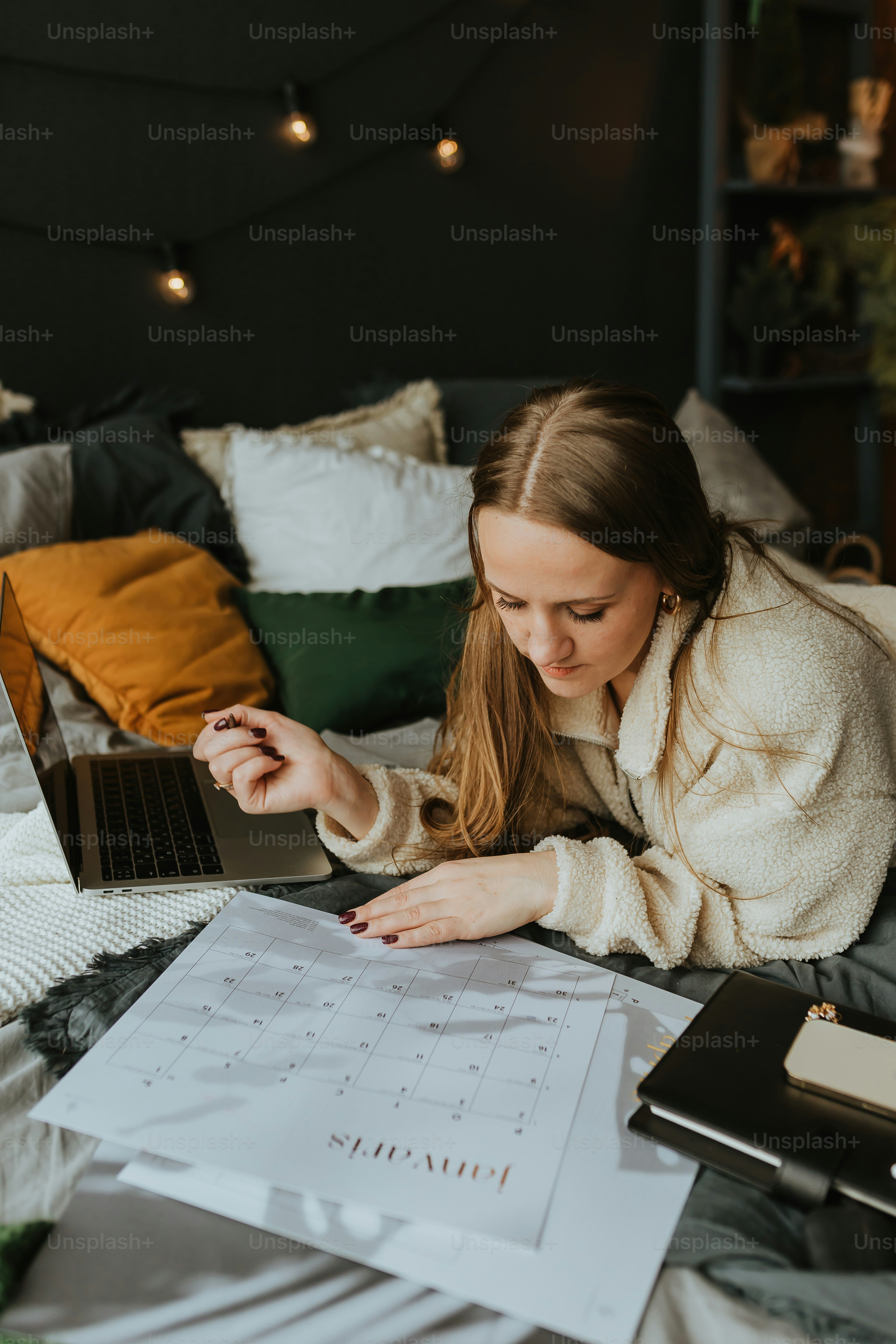 a woman laying on a bed looking at a laptop