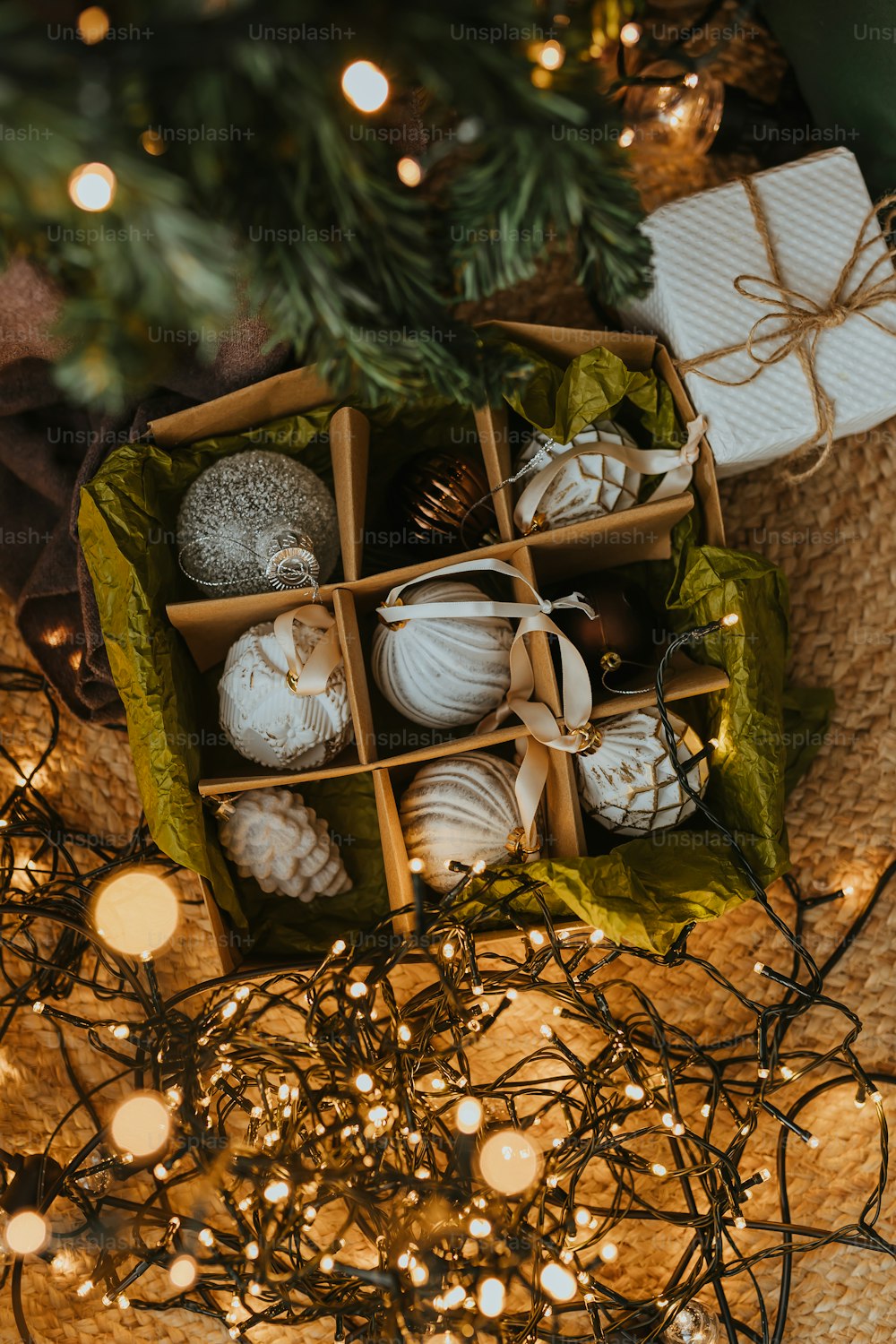 a box filled with christmas ornaments next to a christmas tree