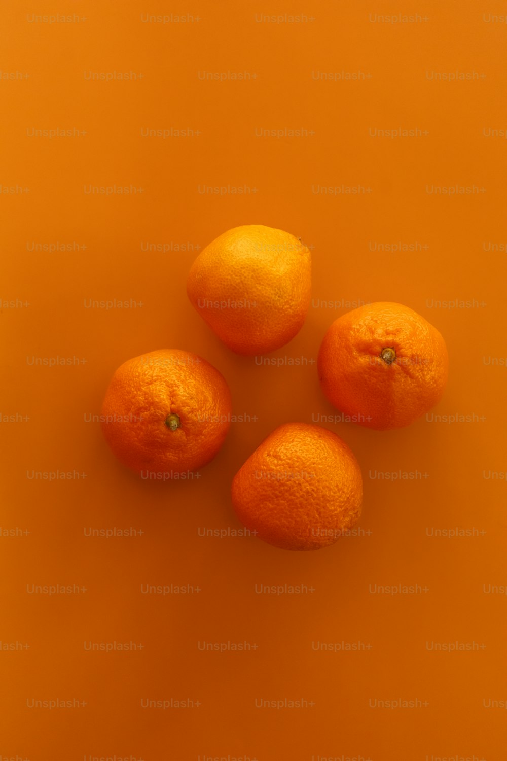 four oranges sitting on top of an orange surface