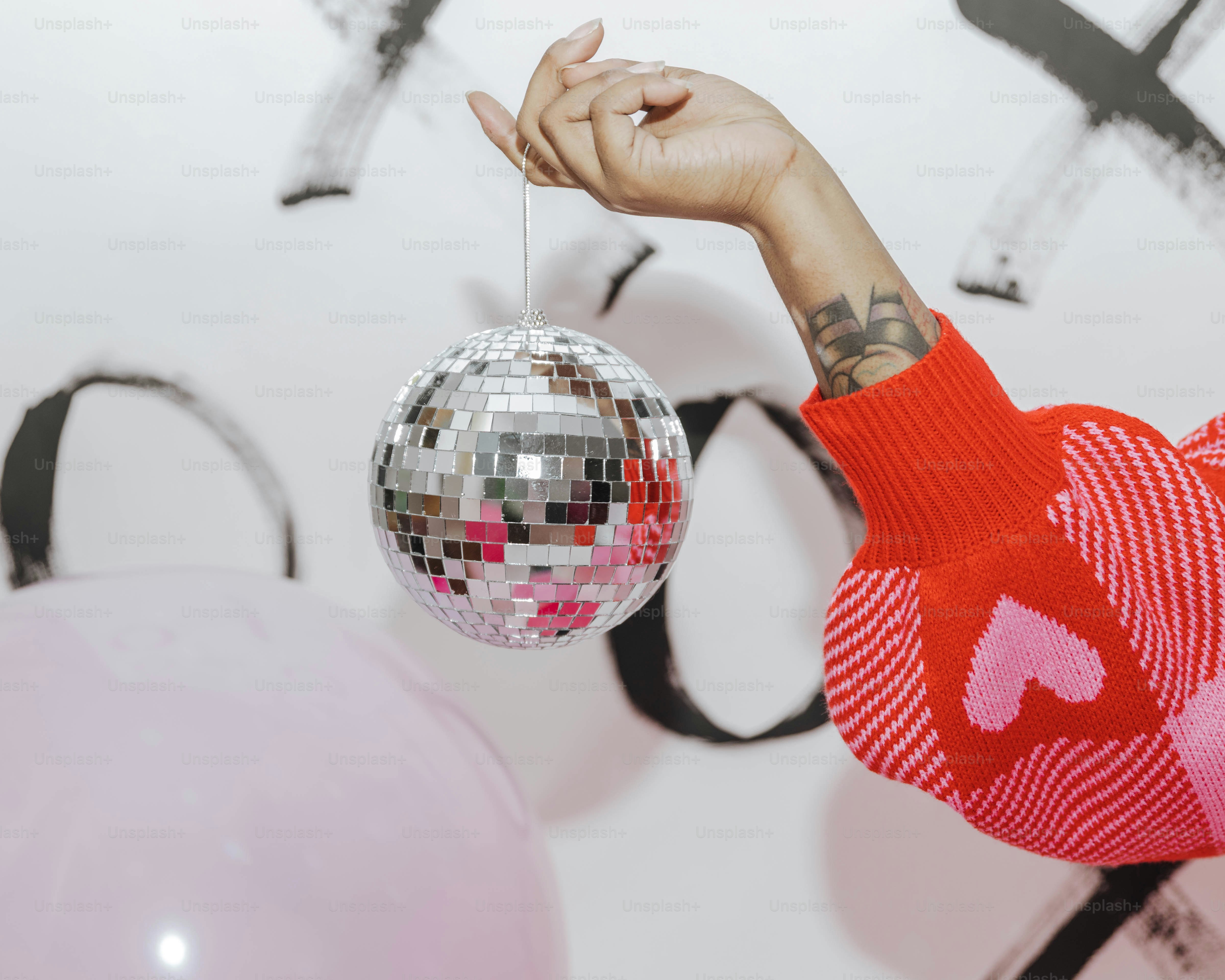 a person holding a disco ball in front of a wall