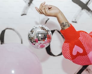 a person holding a disco ball in front of a wall