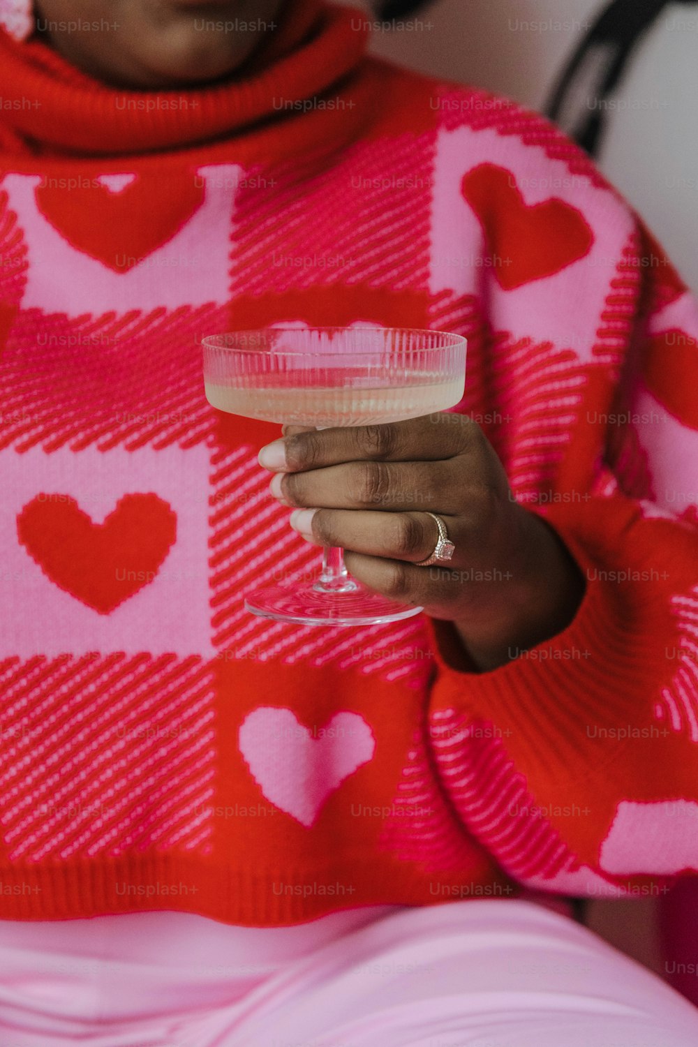 a woman in a pink sweater holding a wine glass