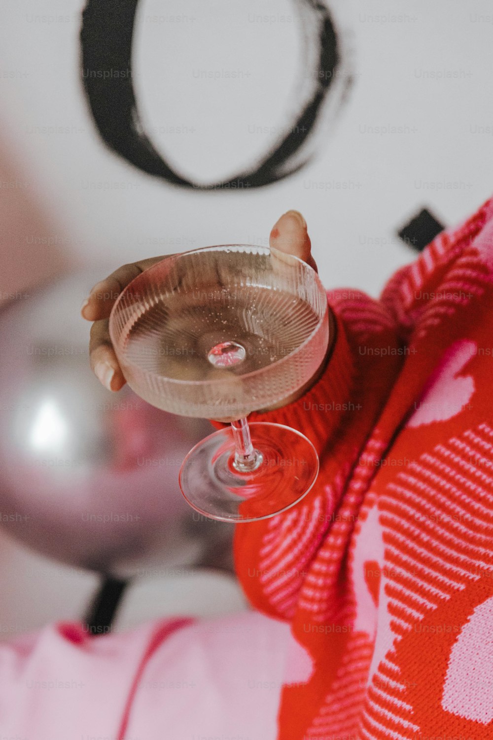 um close up de uma pessoa segurando uma taça de vinho