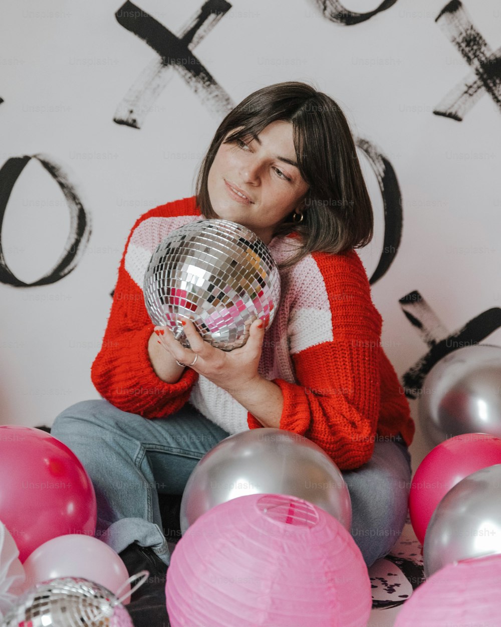 a woman sitting on the floor holding a disco ball