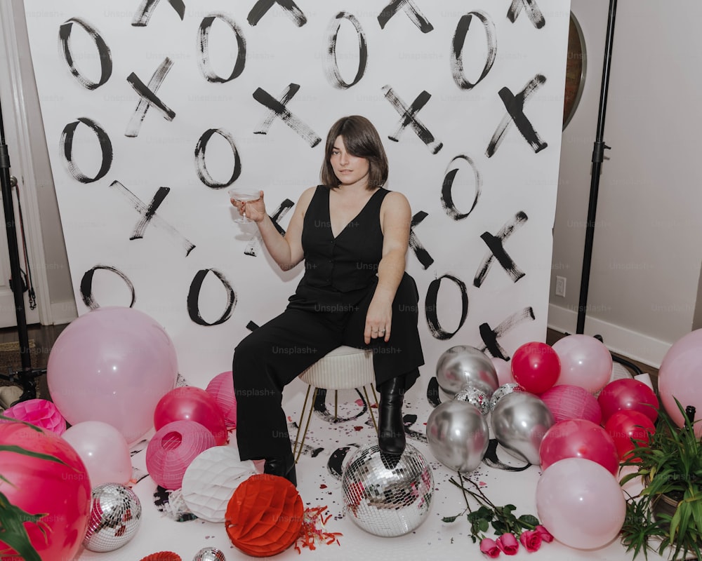 a woman sitting on a chair surrounded by balloons
