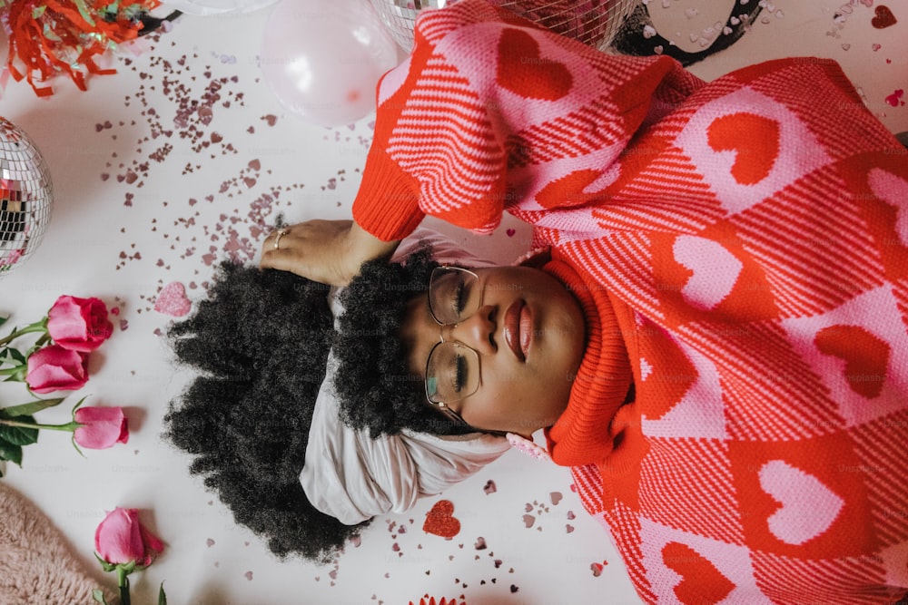 분홍색과 빨간색 하트로 덮인 침대에 누워 있는 어린 소녀