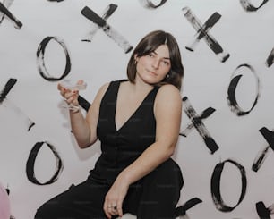 Eine Frau im schwarzen Kleid hält ein Glas Wein in der Hand