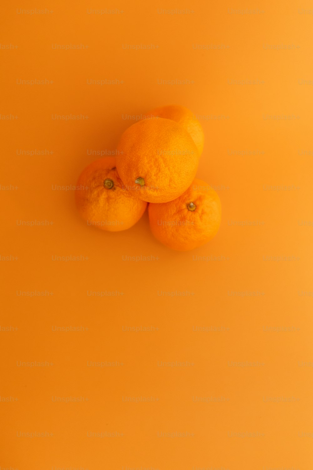 three oranges sitting on top of a yellow surface